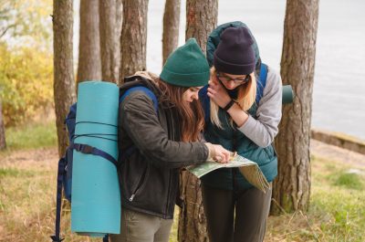 Two young tourist determine the route map and compass.