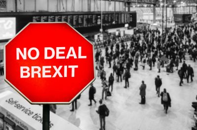 No Deal Brexit written on octagon stop sign with high perspective view defocused passengers at British train station terminal