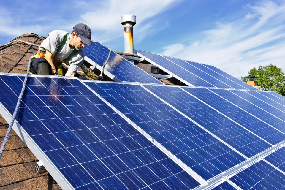 Man installing alternative energy photovoltaic solar panels on roof