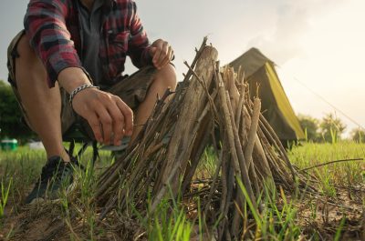 A man tourist making bonfire and set camping tent.