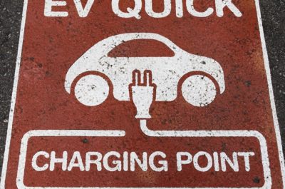Electric vehicle (EV) quick charging point sign on the asphalt at the charging station point
